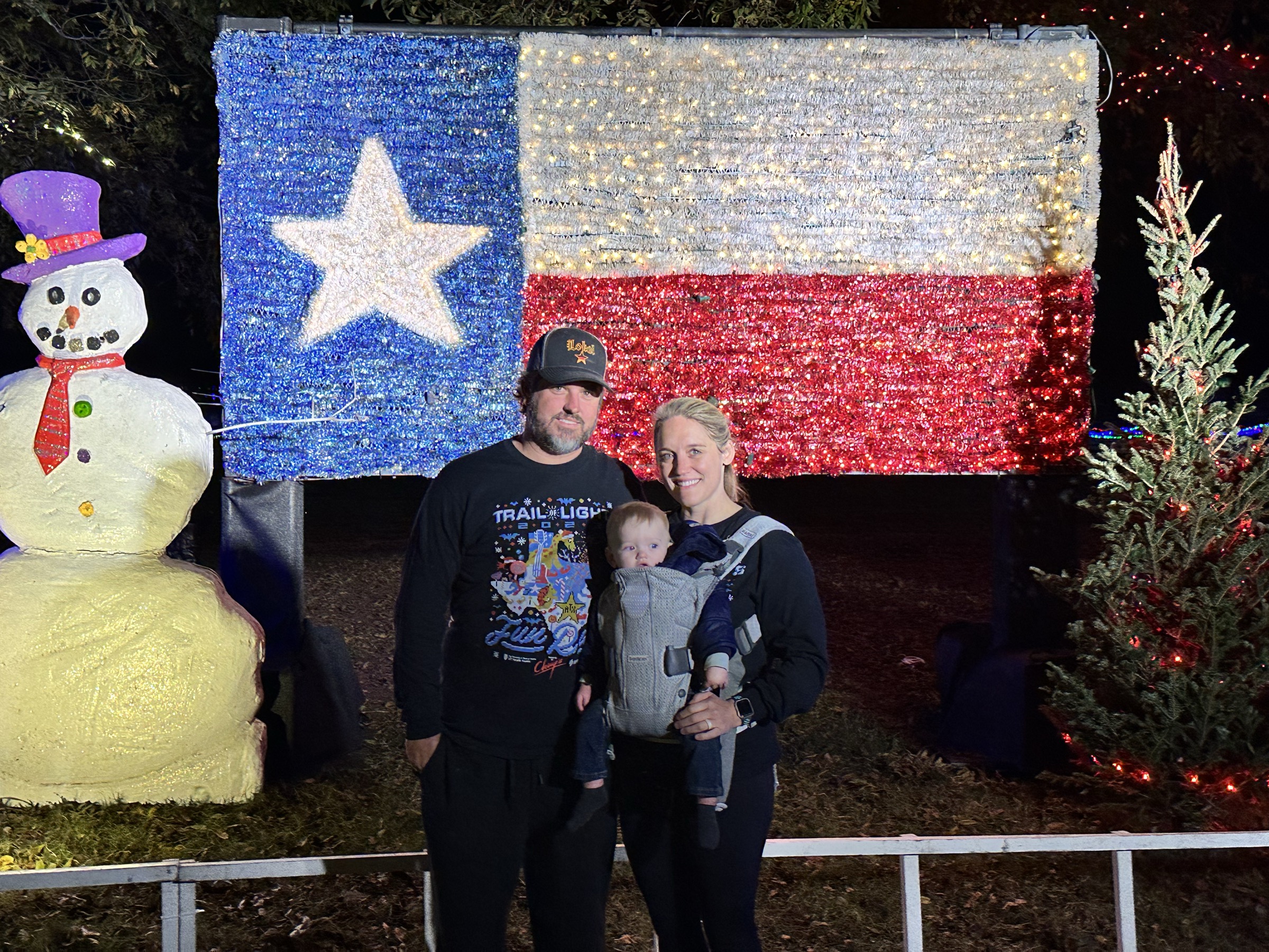 Family in front of the Texas flag display at the Trail of Lights